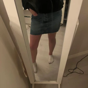 Jeanskjol från Gina Tricot - Snygg jeanskjol från Gina Tricot i klassisk blå denim. Kjolen har en kort längd med rå kant och knappar framtill. Perfekt för en avslappnad stil.