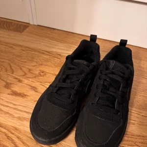 Svarta sneakers från Nike - Snygga svarta sneakers från Nike med perforerad tå och klassisk snörning. Skorna har en diskret Nike-logga på sidan och en tydlig logga baktill. Perfekta för en stilren look. Pris kan diskuteras 