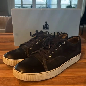 Svarta sneakers från Lanvin - Snygga sneakers från Lanvin med en stilren design. Skorna har en blank tå och snörning framtill. Perfekta för en stilren look. Storlek 46 Uk 11, skriv om du har några funderingar!
