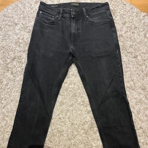Svarta jeans  - Snygga svarta jeans från Jack & Jones med klassisk femficksdesign. De har en normal passform och är perfekta för en stilren look. Tillverkade i slitstarkt denim med en bekväm midwaist.