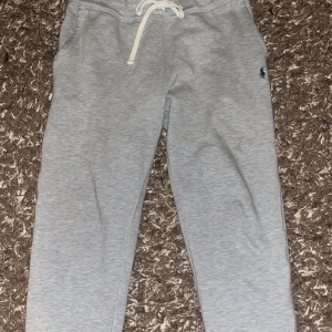 Grå mjukisbyxor från Polo Ralph Lauren - Snygga grå mjukisbyxor från Polo Ralph Lauren med en liten broderad logga på sidan. Byxorna har en bekväm passform med snörning i midjan för justerbarhet. Perfekta för en avslappnad stil. Storlek M, äkta och  kostar 2 tusen nypris