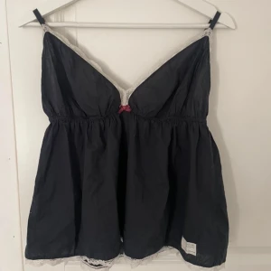 Marinblått linne från Odd Molly - Säljer ett svart linne från Odd Molly med spetsdetaljer och en liten rosett framtill. Linnet har justerbara axelband och en broderad logga på baksidan. Jätte populärt och eftertraktat linne! Väl använt men fortfarande mycket bra skick💞 Storlek 3, och sitter bra på mig med M