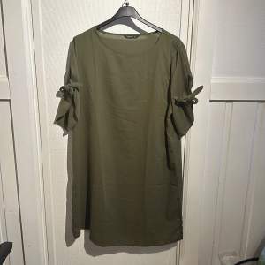 Säljer en olivgrön klänning från Shein Curve i storlek OXL. Klänningen har korta ärmar med knytning och en avslappnad passform. Perfekt för en stilren och bekväm look. 🌿