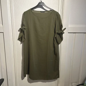 Olivgrön klänning från Shein Curve - Säljer en olivgrön klänning från Shein Curve i storlek OXL. Klänningen har korta ärmar med knytning och en avslappnad passform. Perfekt för en stilren och bekväm look. 🌿