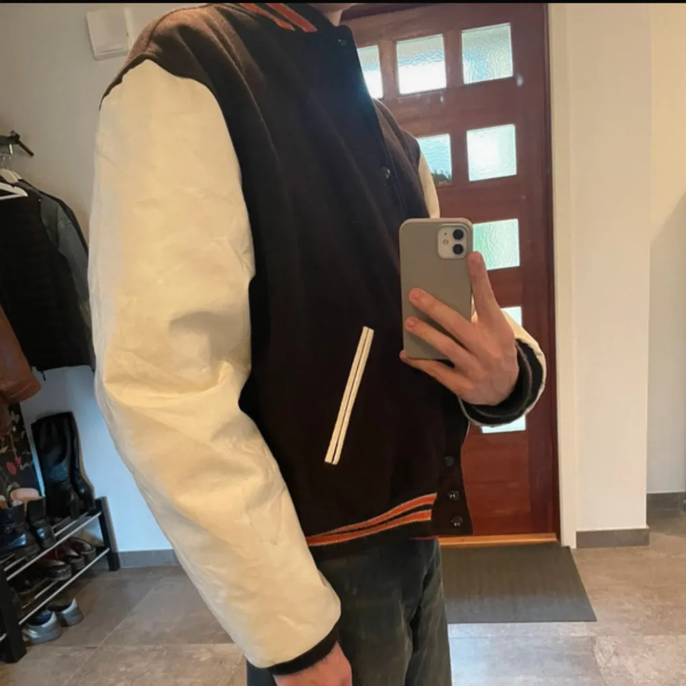 Storlek XL men sitter som en L på mig (186cm), ärmarna är gjorda i vinyl. Jackan är gjord i ull, nylon och polyester och insidan är fodrad så den är varm att ha även på vintern.  Använd men fortfarande i väldigt fint skick. Mått: Axelbredd (57cm), Längd (67,5cm), Armlängd (71cm). Takit.