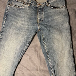 Blå jeans Nudie Jeans - Snygga blå jeans från Nudie med en klassisk design och broderade detaljer på bakfickorna. De har två fickor och en väldigt snygg tvätt. Perfekta för en avslappnad stil. Storlek: W33 L34