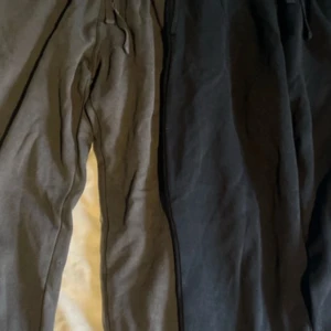 Svarta och gråa mjukisbyxor från H&M - Två par mjukisbyxor från H&M i svart och grått. De har en elastisk midja med snörning för justerbar passform. Perfekta för en avslappnad stil.