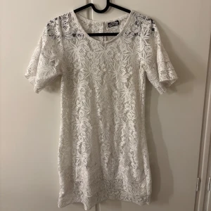 Vit spetsklänning från BikBok - Säljer en elegant vit spetsklänning från BikBok. Klänningen har korta ärmar och ett vackert blommigt mönster. Perfekt för sommarens alla tillfällen. 🌸
