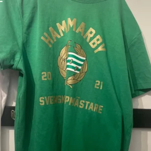 Grön Hammarby t-shirt från Craft - Säljer en grön t-shirt från Craft med Hammarby-tryck och texten 'Svenska Mästare 2021'. T-shirten är kortärmad och tillverkad i en blandning av bomull och polyester. Perfekt för alla Hammarby-fans! 💚