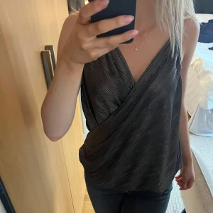 Glittrigt Svart omlottlinne - Säljer ett svart omlottlinne med tunna axelband. Pris kan diskuteras 