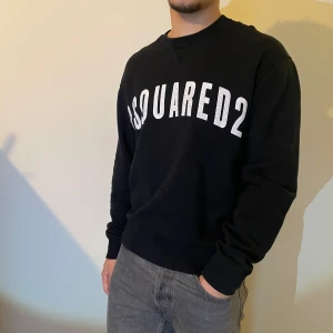 Svart tröja från Dsquared2 - Snygg svart tröja från Dsquared2 med vit text på bröstet. Tröjan har långa ärmar och en klassisk passform. Perfekt för en stilren look.