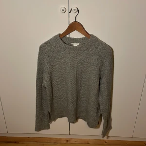 Grå stickad tröja i S från H&M - Säljer en mysig grå stickad tröja från H&M. Perfekt för kyliga dagar med sin mjuka och bekväma passform. Tröjan har långa ärmar och en klassisk rund halsringning samt en slitt på sidorna.  Ett måste i garderoben för en stilren look.