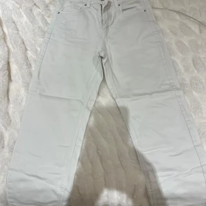 Vita jeansbyxor - Snygga vita jeansbyxor med klassisk design. De har en rak passform och är perfekta för en stilren look. Byxorna har fickor både fram och bak samt en dragkedja framtill.