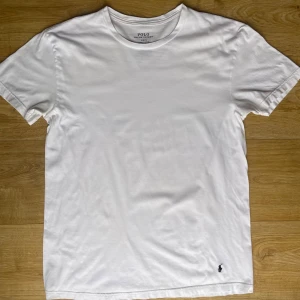Vit t-shirt från Polo Ralph Lauren - Säljer en klassisk vit t-shirt från Polo Ralph Lauren. Den har en liten broderad logga i svart på framsidan. Perfekt basplagg för alla tillfällen. Tillverkad i mjuk bomull för extra komfort.