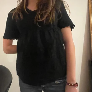 Svart kortärmad topp - Säljer en stilren svart topp med detaljer och korta ärmar. Aldrig använd, endast testad.