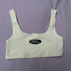 Vit topp från h&m - Säljer en vit topp från h&m med breda axelband och ett tryck framtill. Perfekt för en avslappnad stil. Toppen är i ett mjukt och bekvämt material.