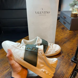 Valentino Garavani sneakers  - Exklusiva Valentino Open sneakers i vitt med grönt sträck! En stilren och tidlös modell som passar perfekt både till vardags och mer uppklädda tillfällen.  | Färg: Vit, grön⚪️💚✨ | Skick: Använt skick med en liten defekt framme vid tårna 👍 | Modell: Open 🏆 | Storlek: 43 👌 | Box: Originalbox medföljer 📦 | 🚚 Leverans: Skickas snabbt via PostNord eller Instabox 📬📦 |  💬 Skicka ett meddelande vid frågor!
