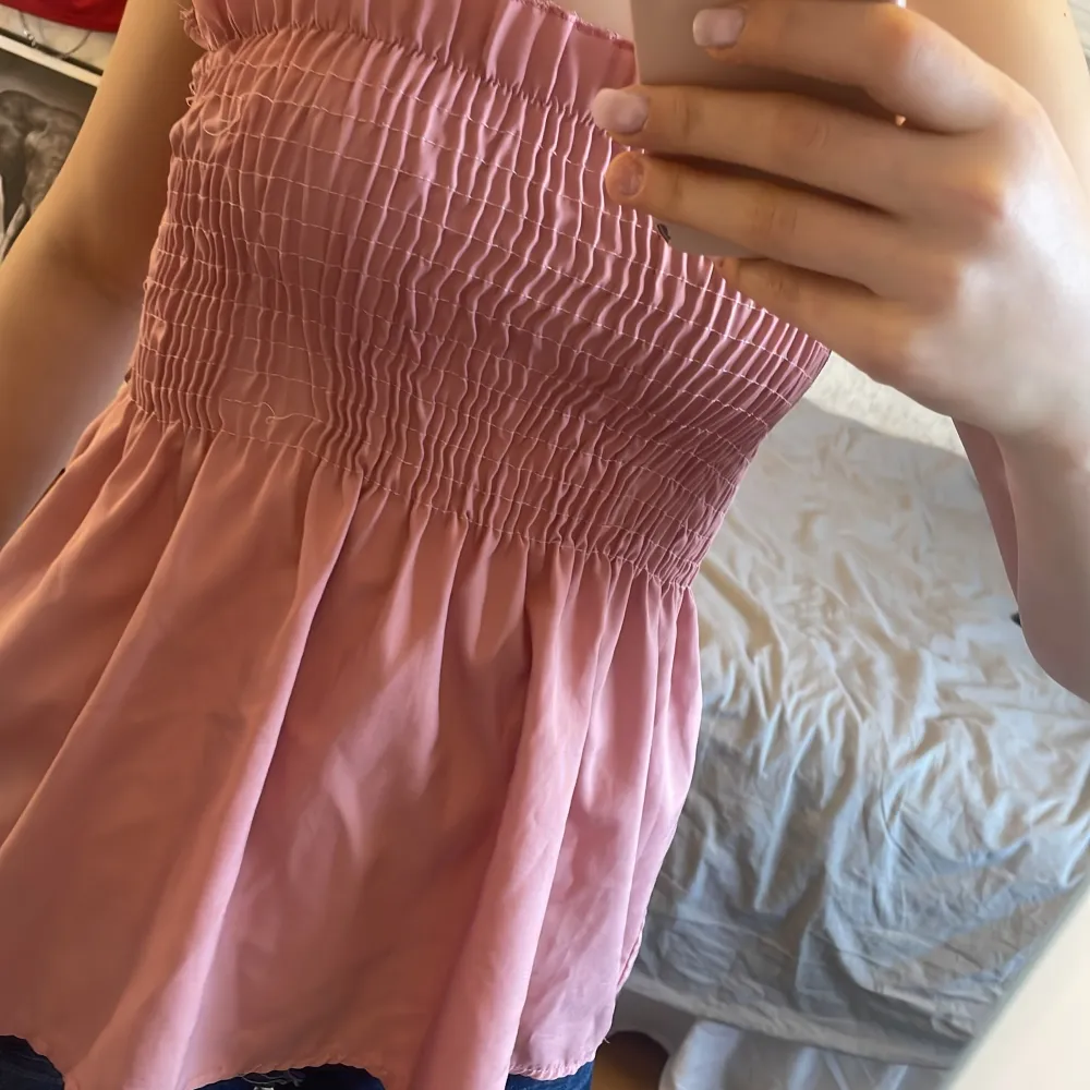Säljer en söt rosa tubtoppmed smockdetaljer i midjan som ger en bekväm passform. Kjolen har en luftig och fladdrig design som passar perfekt för varmare dagar. Perfekt för att skapa en avslappnad och stilren look.. Puserot.