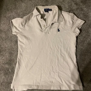 Vit piké  från Ralph Lauren - Säljer en klassisk vit piké  från Ralph Lauren i skinny fit. Piken har korta ärmar och en liten broderad logga på bröstet. Perfekt för en stilren look.  Tveka inte på att höra av dig