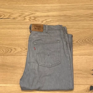Grå jeans från Levi's - Snygga grå jeans från Levi's med klassisk femficksdesign och en bekväm passform. Perfekta för en stilren look. Levi's logotyp på bakfickan ger en autentisk touch.