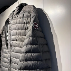 Grå dunjacka från Colmar - Säljer en stilren grå pufferjacka från Colmar. Jackan har en quiltad design med dragkedja framtill och långa ärmar. Perfekt för kyligare dagar med sin lätta och bekväma passform.