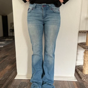Ljusblå, bootcut jeans från Bondelid - Snygga ljusblå bootcut jeans från Bondelid. Lågmidjade med små lila detaljer. 160 cm lång modell. Står ingen storlek men tycker XS-S. Innerbenslängd: 80/81 cm. Midjemått: 34 cm rakt över. Köpta secondhand men fint skick. Om du har frågor elelr vill ha mer bilder kontakta mig🩷