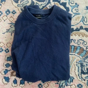 Mörkblå tröja från Massimo Dutti - Säljer en stilren mörkblå tröja från Massimo Dutti. Tröjan har en klassisk design med rund hals och långa ärmar. Perfekt för en avslappnad men ändå elegant look. Passar bra till både jeans och chinos. Värt att nämna att den har en lagning på ett stygn vid kragen som inte lägga märke till. Fråga gärna efter fler bilder osv.