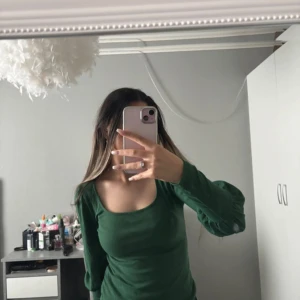 Grön ribbad topp - Säljer en snygg grön ribbad topp med långa ärmar. Toppen har en rund halsringning och är perfekt för både vardag och speciella tillfällen. Passar bra till jeans eller kjol för en stilren look.