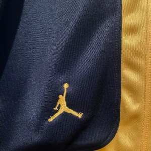 Svarta och gula shorts från Jordan - Snygga svarta och gula shorts från Jordan med det ikoniska logotypen broderad i gult. Shortsen har en elastisk midja för en bekväm passform. Strl M kan användas även unisex 