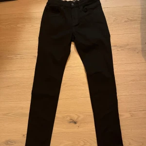 Svarta byxor från Lindex - Snygga svarta byxor från Lindex i en klassisk design. De har en rak passform och är perfekta för en stilren look. Byxorna är tillverkade i ett bekvämt material och har en midwaist design.