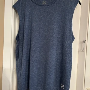 Blå ärmlös linnetopp från X-Trail - Säljer en blå ärmlös linnetopp från X-Trail. Perfekt för träning med sin bekväma passform och stilrena design. Toppen har ett diskret mönster och logga på framsidan. Passar utmärkt för aktiva dagar.