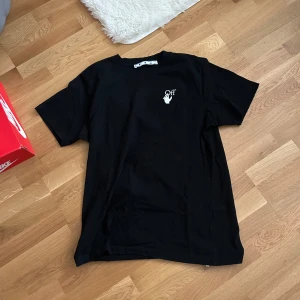 Svart t-shirt med tryck från Off-White - Snygg svart t-shirt från Off-White med ett litet vitt tryck fram och ett stort färgglatt tryck i lila och rosa på baksidan. Perfekt för dig som vill ha något unikt och trendigt i garderoben.