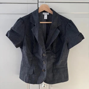 Kavaj/topp - Kortärmad kavaj som är perfekt som festtopp. Jättefin krage och lite lätt figursydd. På gränsen mellan mörkgrå och svart🥰