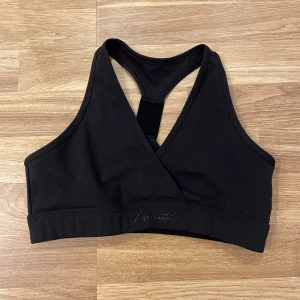 Svart sporttopp Alphalete - Snygg svart sporttopp från Alphalete. Perfekt för träning med sin bekväma passform och stilrena look.