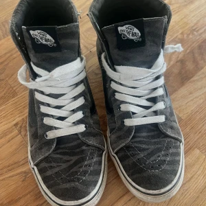 Vans med mönster - Säljer ett par gråa Vans sneakers med zebramönster och vita snören. Skorna har hög modell med klassisk Vans-logga. Storlek US 38,5 women & US 7 men. Så storlek 40 men passar bra på mig som har storlek EU 38,5