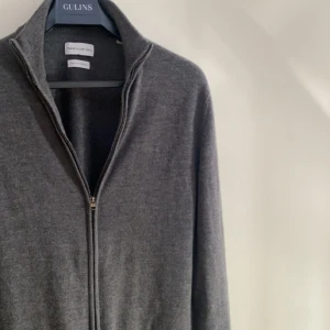 Grå merinoulltröja från These Glory Days - Säljer en stilren grå tröja i merinoull från These Glory Days. Tröjan har en dragkedja framtill och en hög krage, perfekt för kyliga dagar. Original pris 1099kr, mitt pris 299kr. Size är S och vid fler funderingar och frågor så nås de på DM