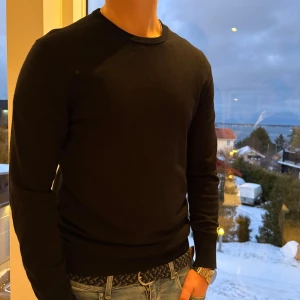 Stickad tröja merinoull  - Säljer en stilren svart tröja från Uniqlo. Tröjan har en klassisk design med långa ärmar och rund hals. Perfekt för en avslappnad look. Den är i merinoull. Passar bra till nästan allt. Den är i bra skick. Bara att fråga om ni undrar något.
