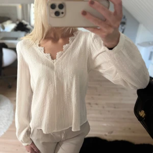 Vit långärmad blus från Vila - Aldrig använd men prislapp borttagen!Fräsh vit långärmad blus, perfekt nu till våren!🤩den har spetsdetaljer längs v-ringningen och är gjord i ett mjukt tunt material. 