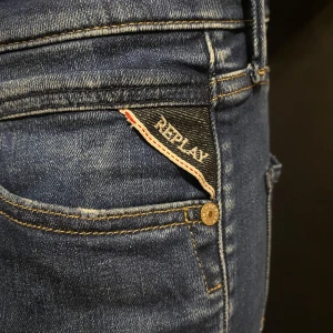 Blå jeans från Replay - Snygga blå jeans från Replay med klassisk femficksdesign och guldfärgade sömmar. Jeansen har en slim passform och är tillverkade i slitstarkt denim. Perfekta för en stilren look.  Modellen donny W30 L32.               