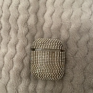 Glittrigt AirPods-fodral - Snyggt och glittrigt AirPods-fodral täckt med små, glänsande stenar. Perfekt för att ge dina AirPods en lyxig och unik look. Fodralet är designat för att passa standard AirPods och ger ett bra skydd mot repor och stötar.