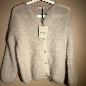 Beige kofta från Design by Si - Mysig beige kofta från Design by Si med knappar framtill. Aldrig använd och lappen kvar💕materialet är mohair