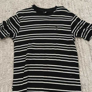 Svart och vit randig t-shirt - Säljer en stilren svart och vit randig t-shirt med korta ärmar. Perfekt för en avslappnad look. T-shirten har en klassisk passform och är gjord i ett mjukt material för extra komfort.