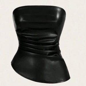 Svart tubtopp i skinnimitation - Snygg svart tubtopp i skinnimitation med en stilren och modern design. Toppen har en asymmetrisk nederkant och fina rynkdetaljer på sidan . Är helt oanvänd då den var för stor.