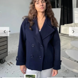 Mörkblå kappa från design by si - Snygg mörkblå kappa med dubbelknäppning och bred krage. Jackan har långa ärmar med dekorativa knappar vid ärmsluten. Perfekt för kyligare dagar och ger en stilren look. Den är sparsamt använd men har blivit lite nopprig , jag ska försöka få bort de mesta sedan kan man alltid använda sig av en nopprings maskin om man har de hemma 🤩🙌🏼😍Storleken är i XS/S  skriv privat för bilder på den jag säljer 