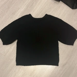 Svart stickad tröja - Säljer en enkel och stilren svart stickad tröja med trekvartsärm. Perfekt för kyligare dagar och lätt att matcha med olika outfits.