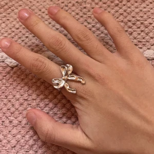 Silverfärgad ring med rosett - Elegant silverfärgad ring med en dekorativ rosett. Perfekt för att ge en stilfull touch till din outfit. Rosetten ger en unik och charmig detalj.