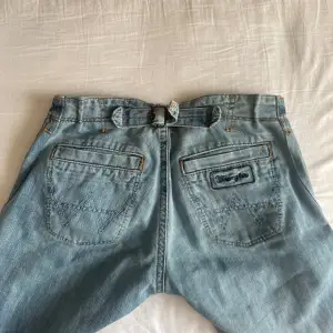 Supersnygga lågmidjade jeans från märket ”Wrangler” som är min mammas gamla. De är lite utsvängda i modellen. Midjemått: 34cm rakt över (går att spänna ut där bak) Innerbenslängd: 77cm