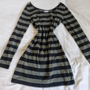 Randig klänning från Miss Milla - Säljer en superfin randig klänning från Miss Milla i storlek M. Den har ett klassiskt svart och grågrönt randigt mönster och är långärmad med urringning. Perfekt för både vardag och fest! Klänningen är i bra skick och har en bekväm passform.