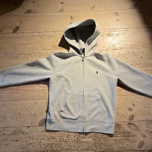 Polo Ralph lauren zip hoodie - skick: som ny. Inga fläckar Eller skador. Material: 84% bomull, 16% polyester. Tyg: Sweatshirttyg. Skötselråd: 30 °C maskintvätt. Nypris: 1000kr.  Storleken är 140-152cm. Kan gå ner i pris vid snabb affär 