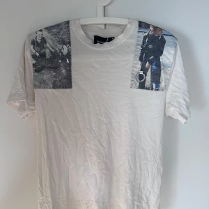 Vit t-shirt från Raf Simons med fototryck - Säljer en stilren vit t-shirt i storlek S från Raf Simons x Fred Perry.  Den är använd men den ända flawn är att de blivit ett litet hål bakom tagen i nacken. Nypris var 1500. säljer för 500. 